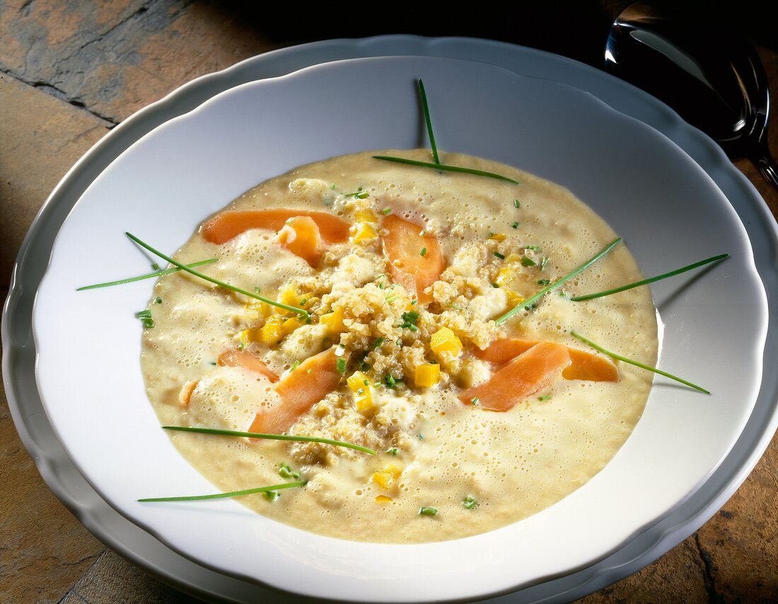 Bowl of parsley root soup with paprika, chives and quinoa in bowl