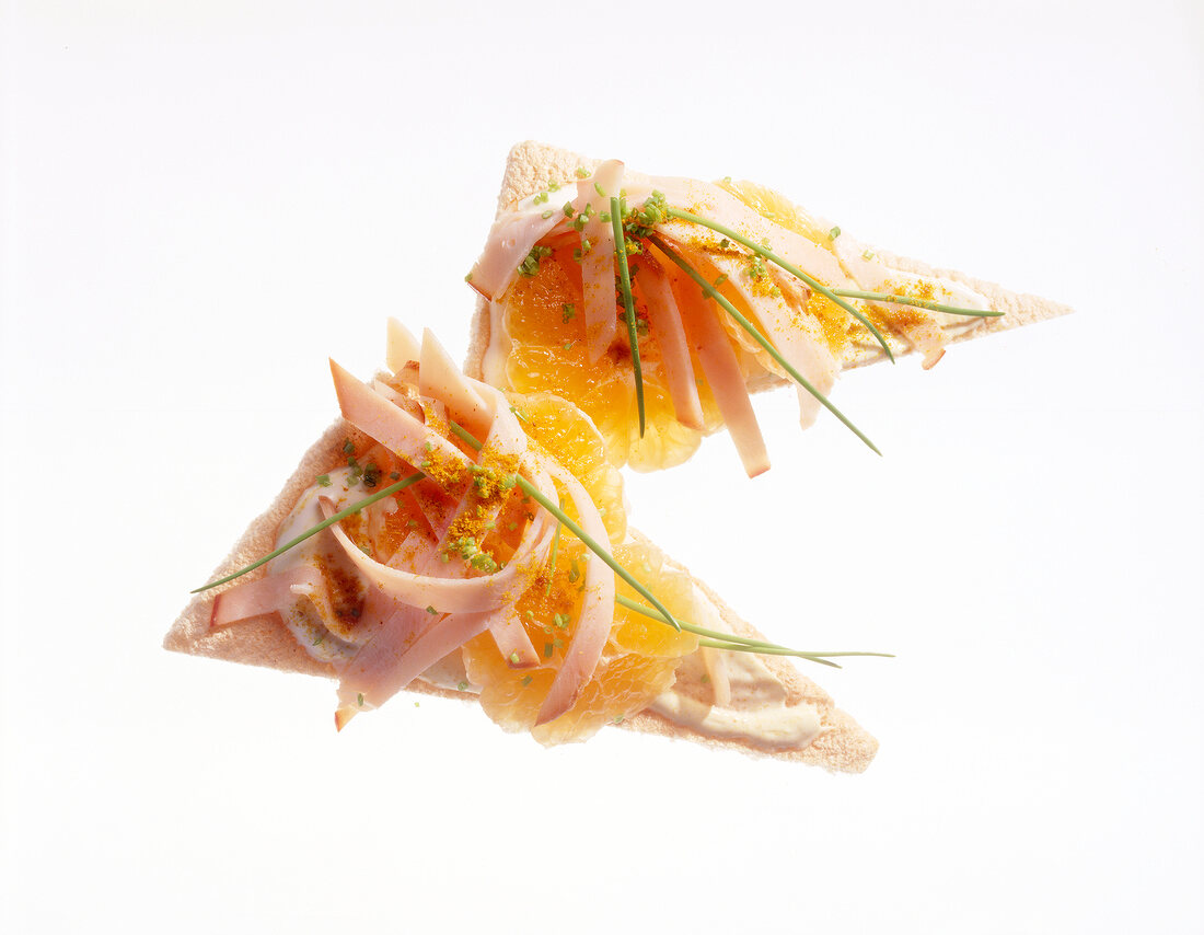 Crisp bread with turkey breast, chives and mandarin on white background