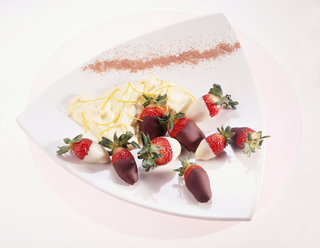 Erdbeeren in Schokolade mit Creme und Zitronenschalenstreifen
