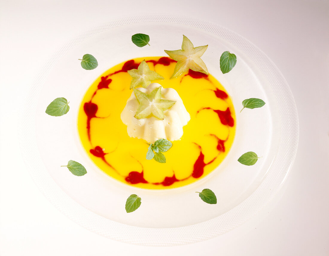 Apricot puree with vanilla cream and karambola on plate decorated with herbs