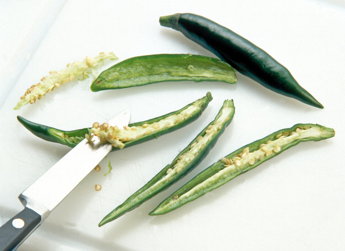 Peppers cut in half and seeded with knife on white surface