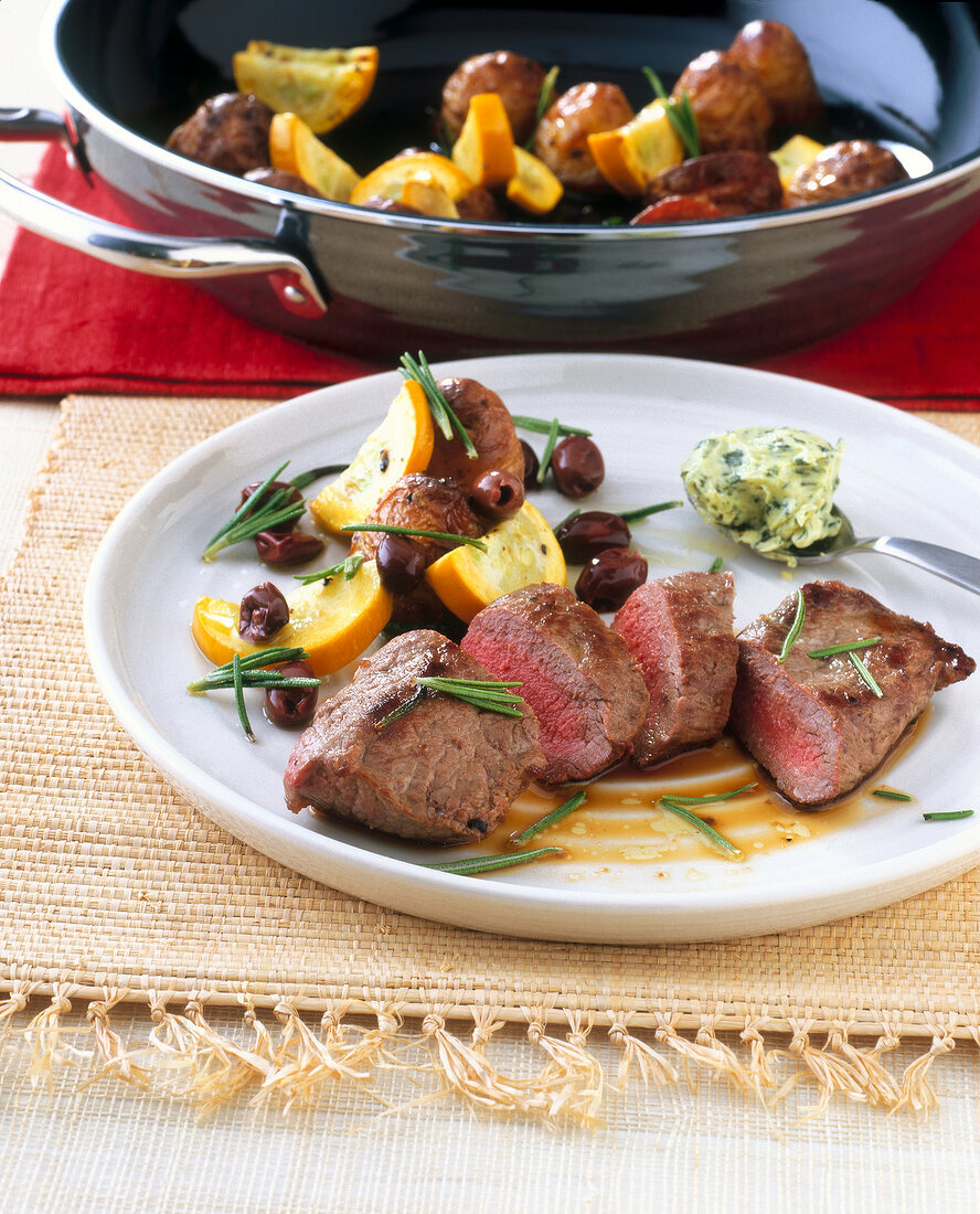 Lamb steaks and olive potatoes garnished with herbs on plate