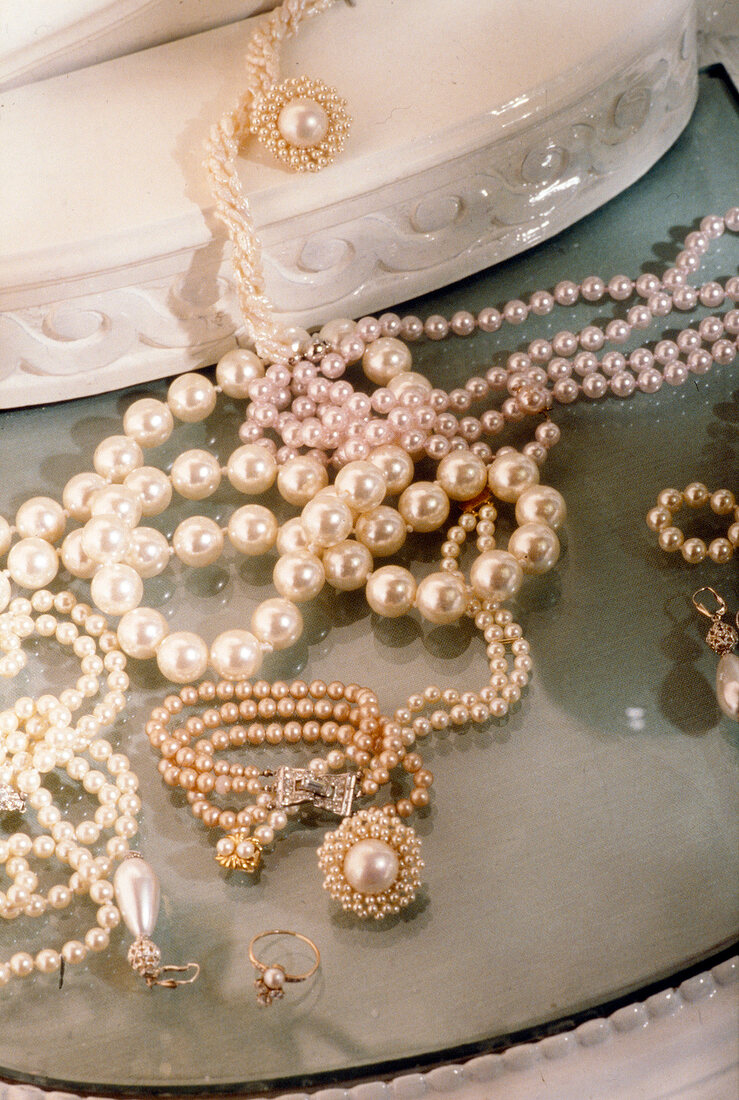 Close-up of various pearl jewellery on glass table