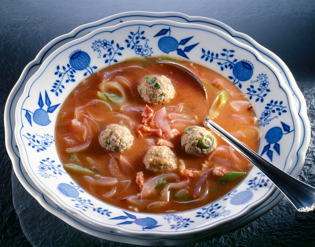 Bowl of onion soup with meatballs and tomato paste