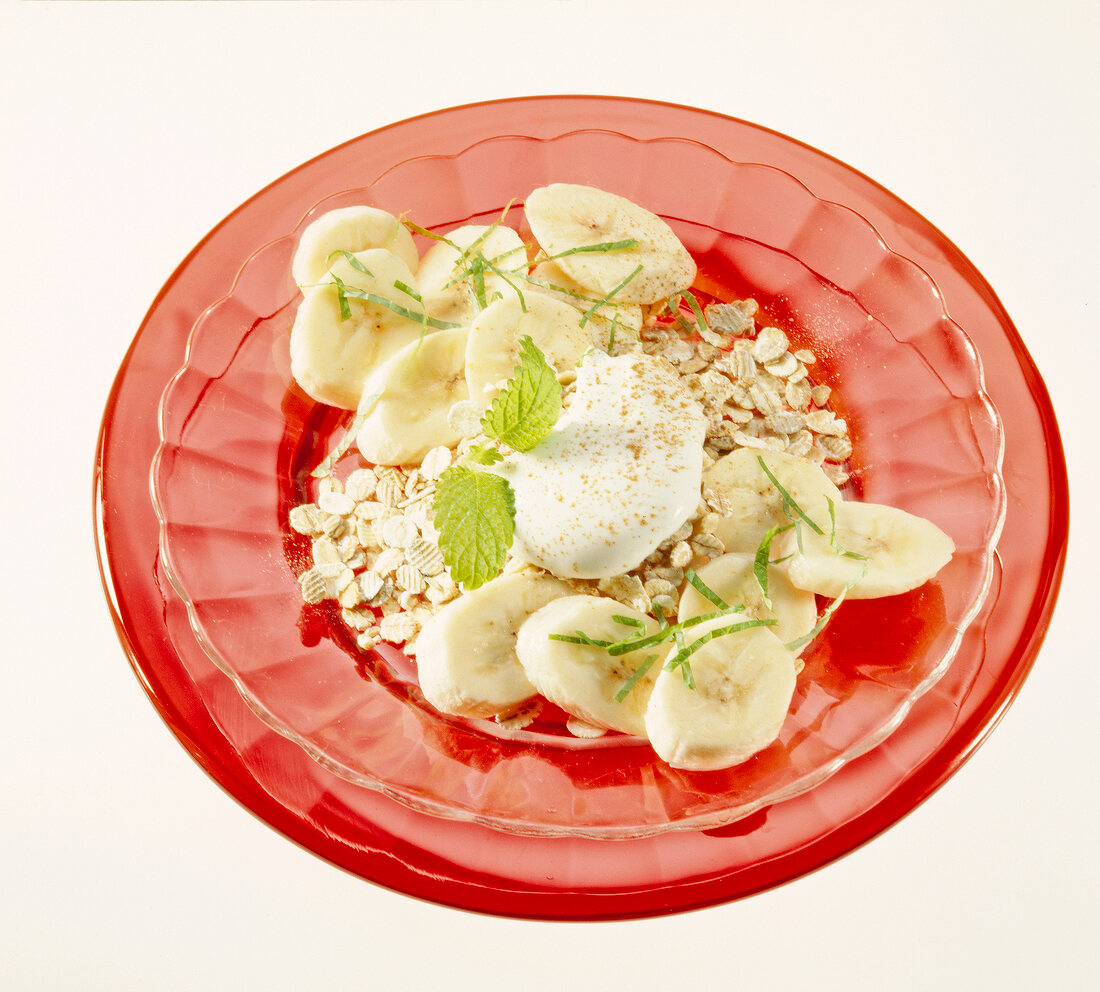 Cereal with banana and mint on red plate
