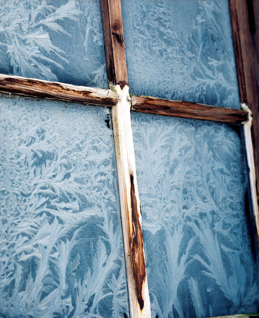 Holzfenster mit Eisblumen auf der Glasscheibe