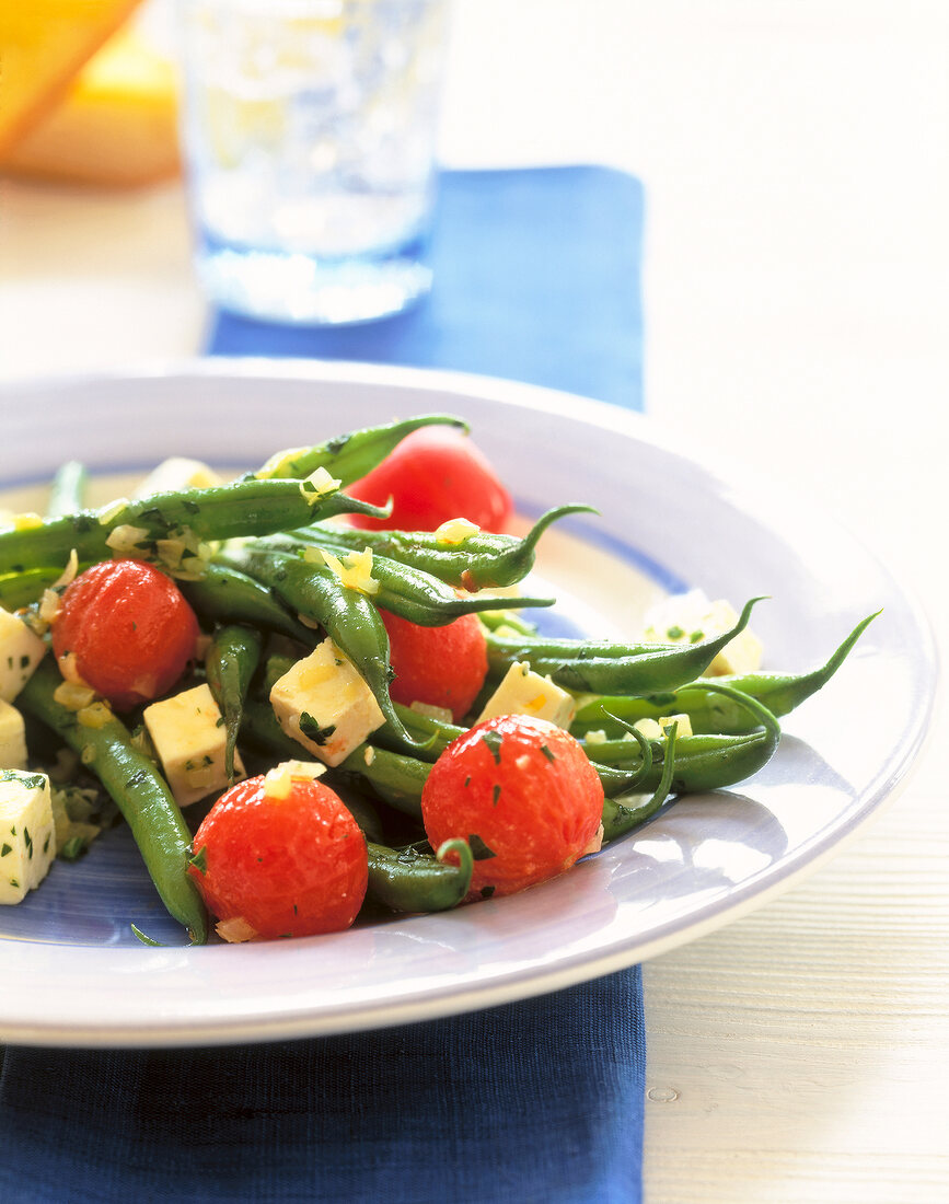 Close-up of green beans with feta and tomatoes on plate