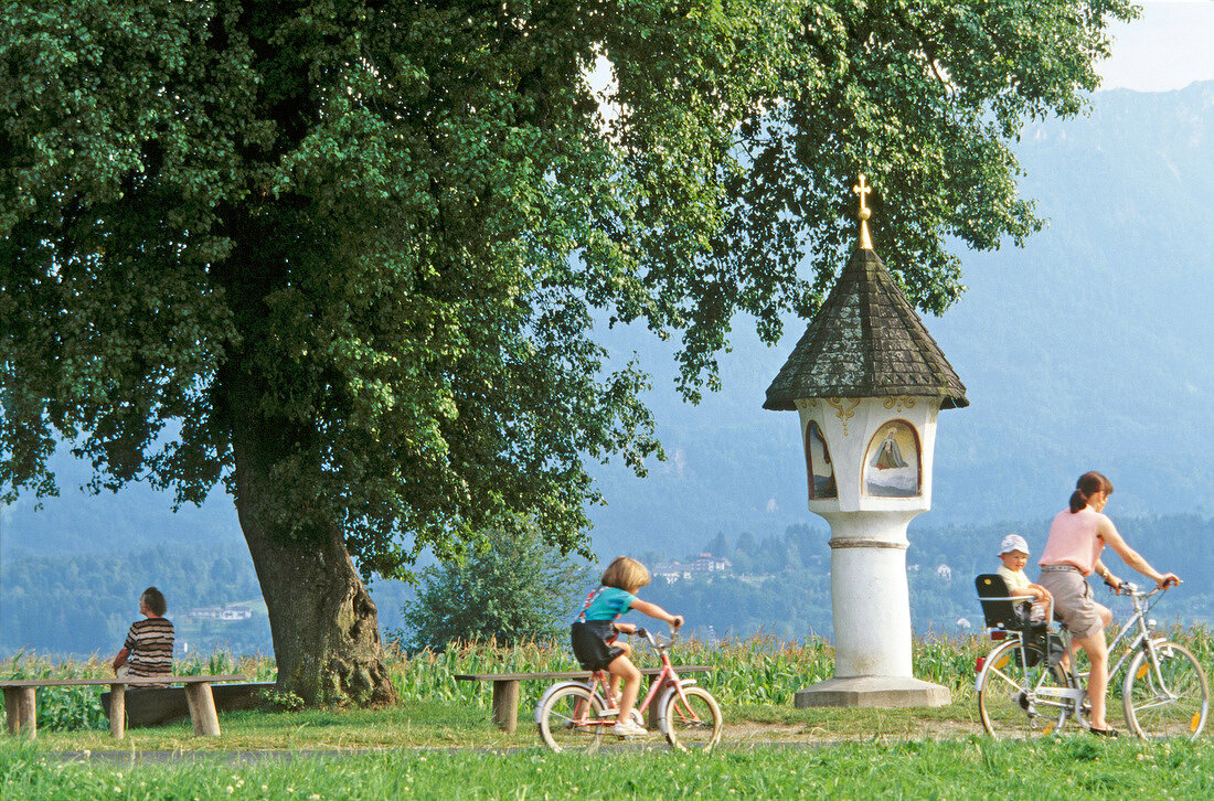 Frau u. 2 Kinder machen e. Fahrradtour, Mann sitzt auf Bank,Österreich