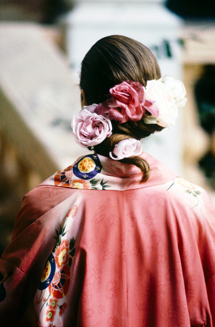 Rear view of woman with updo hair wearing silk roses in hair