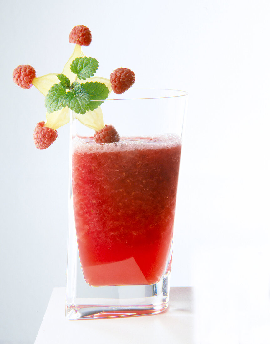 Glass of raspberry juice with carambola on glass edge