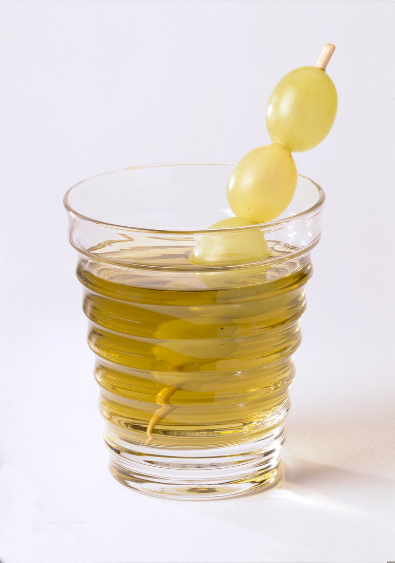 Green nettle drink garnished with grapes in glass