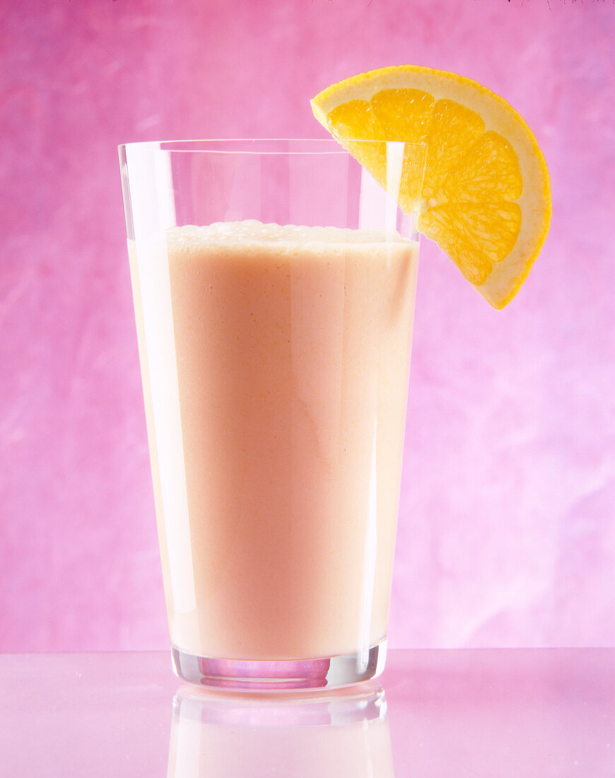 Pfirsich-Orangen-Drink mit einer Orangenscheibe am Glasrand