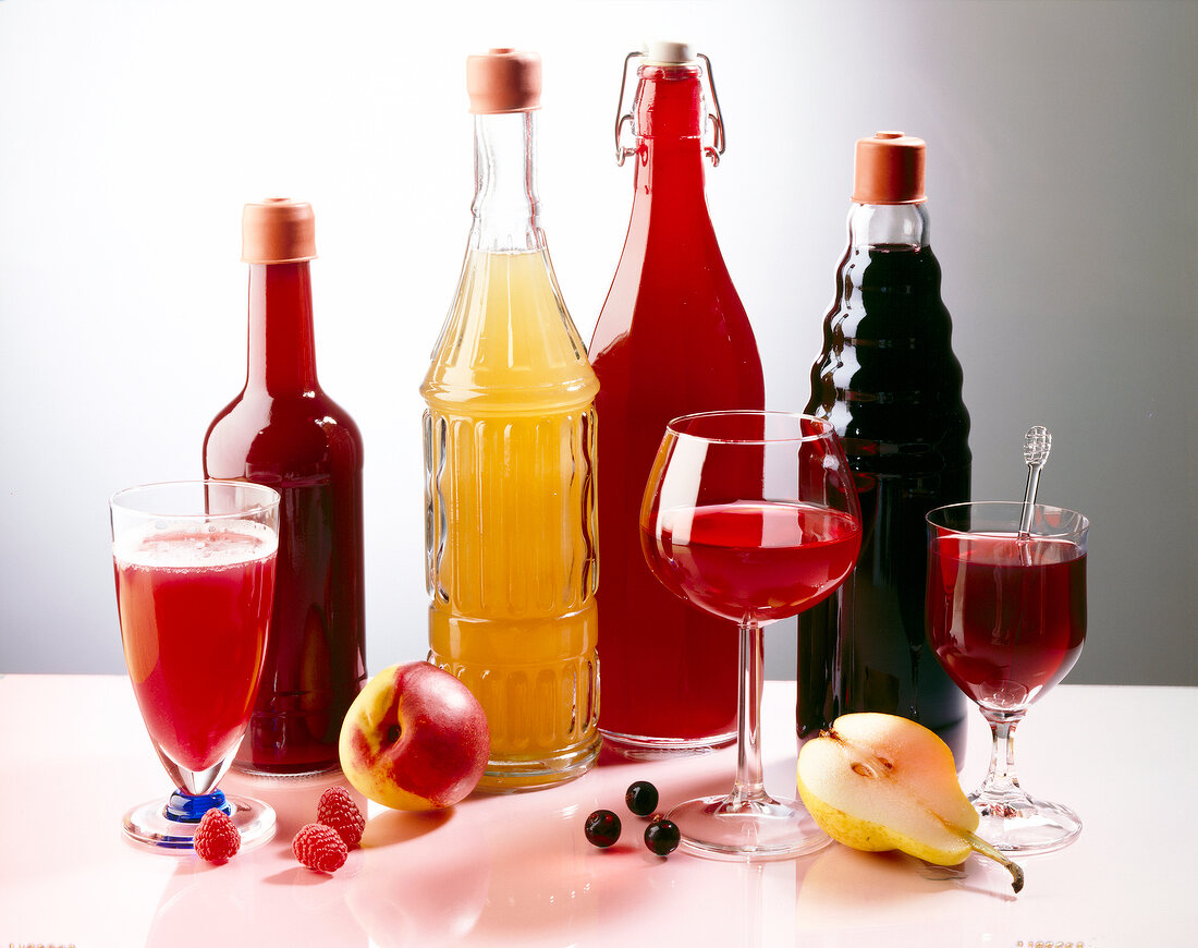Fruit juices in glasses and bottles with fresh pear, apple and berries on table