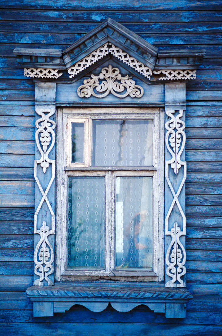 Close-up of typical decorated window on blue wooden house in Russia