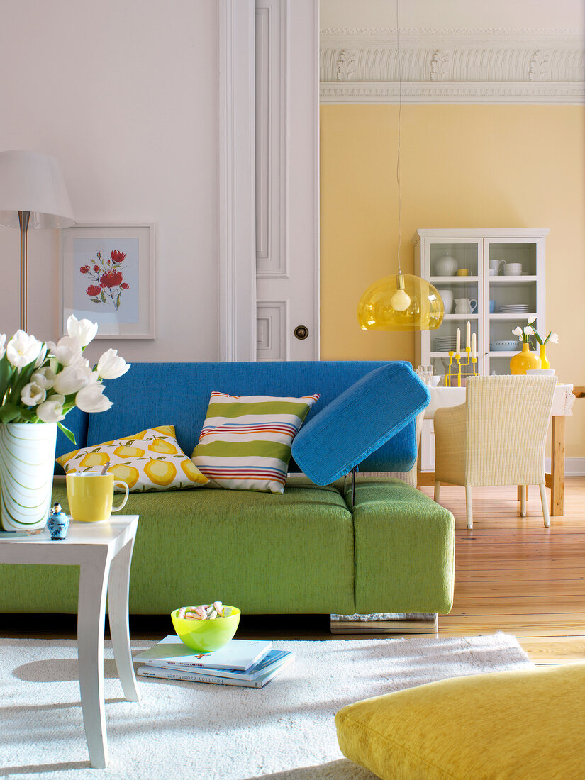 Living room with green sofa and dining room in background