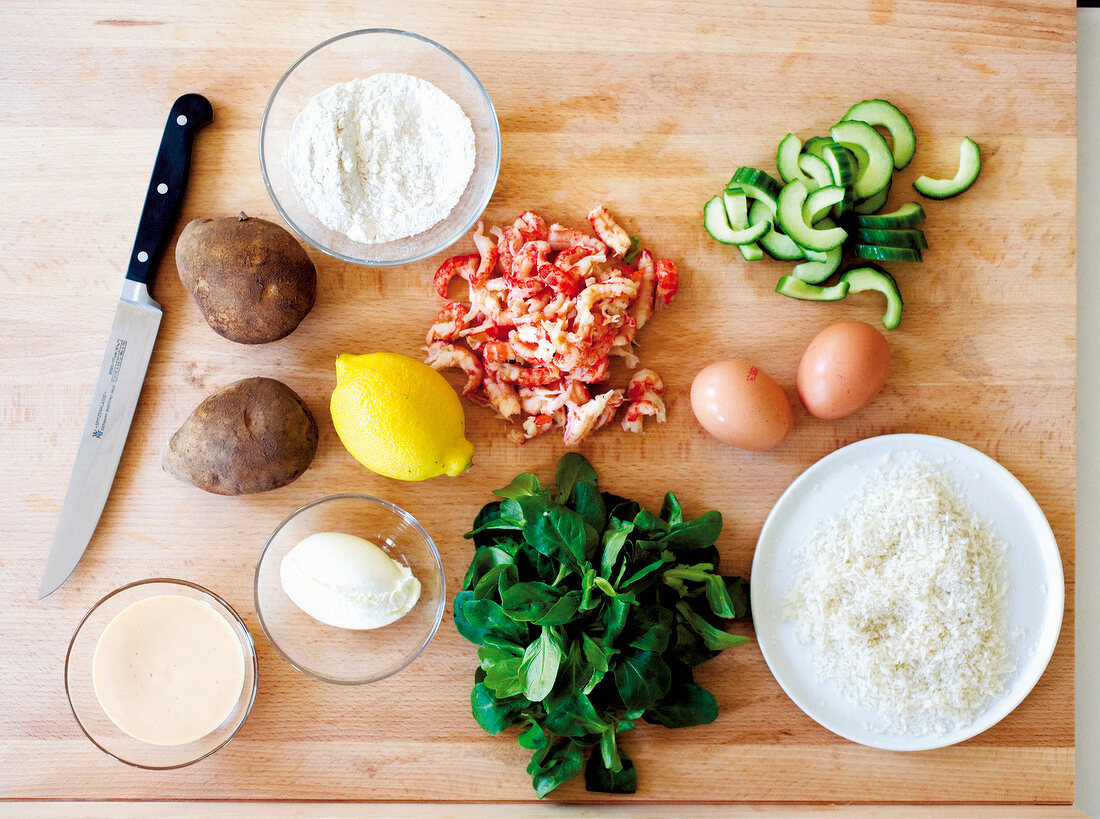 Potatoes, lettuce, cucumber, egg, lemon, crayfish tails and flour on wooden surface