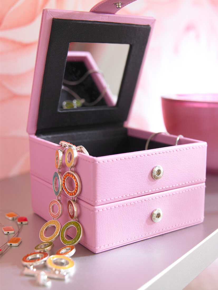 Close-up of pink jewellery box with mirror and jewellery on table