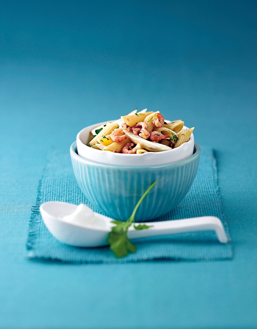 Pasta with fennel, shrimp and vegetables in blue bowl