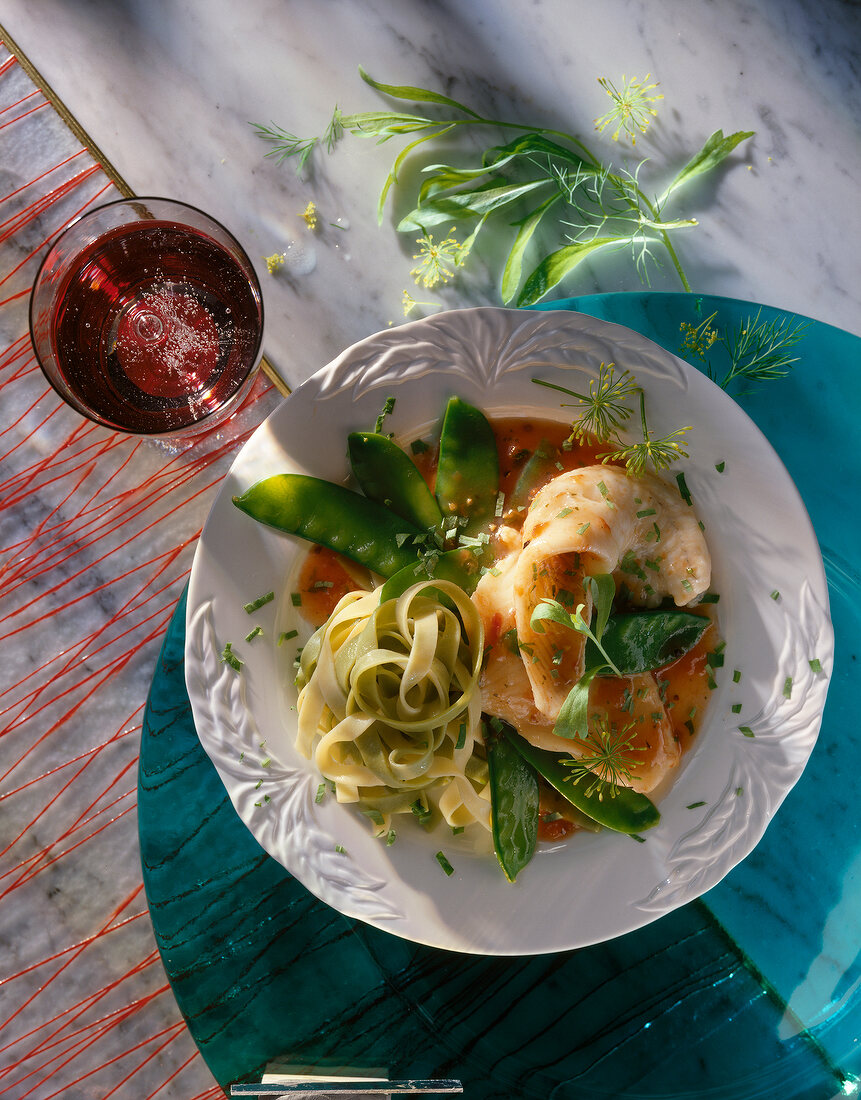 Noodles with fillet of plaice and sugar peas on plate