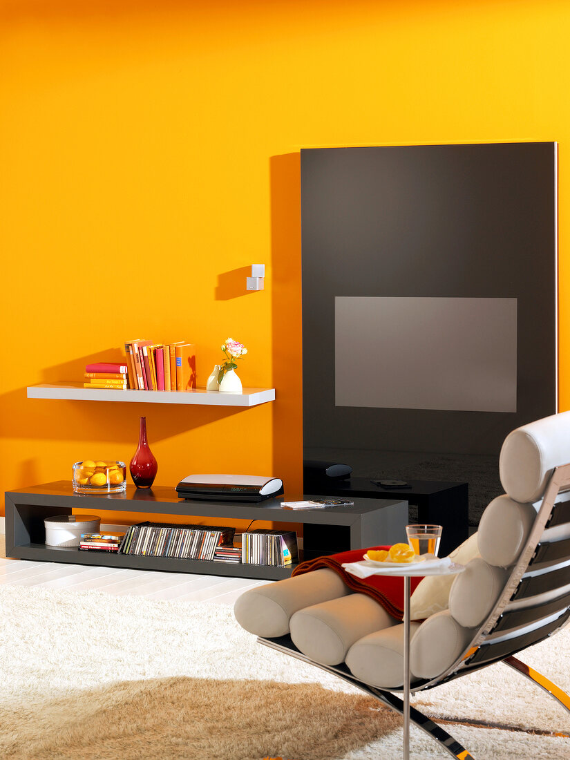 Room with yellow painted wall, recliner, wall unit and TV