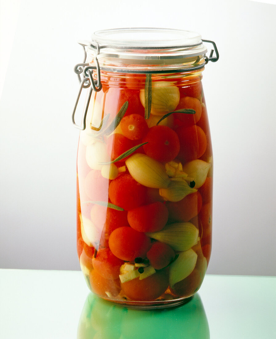 Canned cherry tomatoes and shallots in glass jar