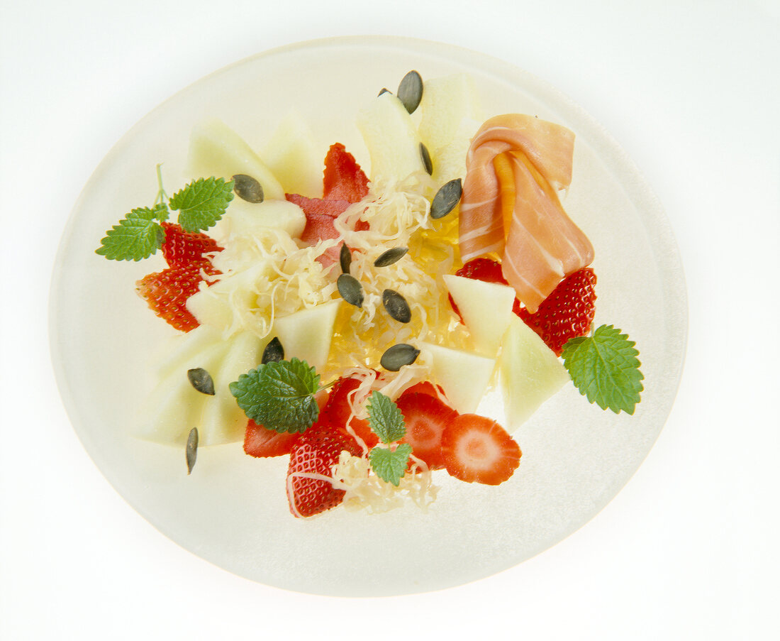 Sauerkraut-Salat mit Erdbeeren, Melone und Schinken auf Teller