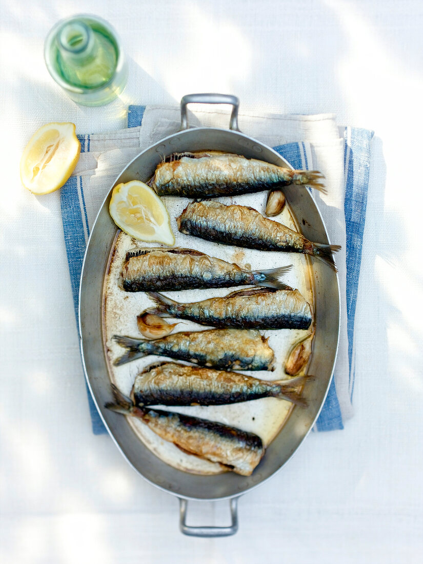 Fried sardines with garlic and lemon in pan