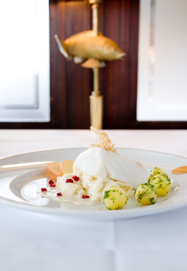 Steamed cod fillet with apple, sauerkraut and potatoes on plate