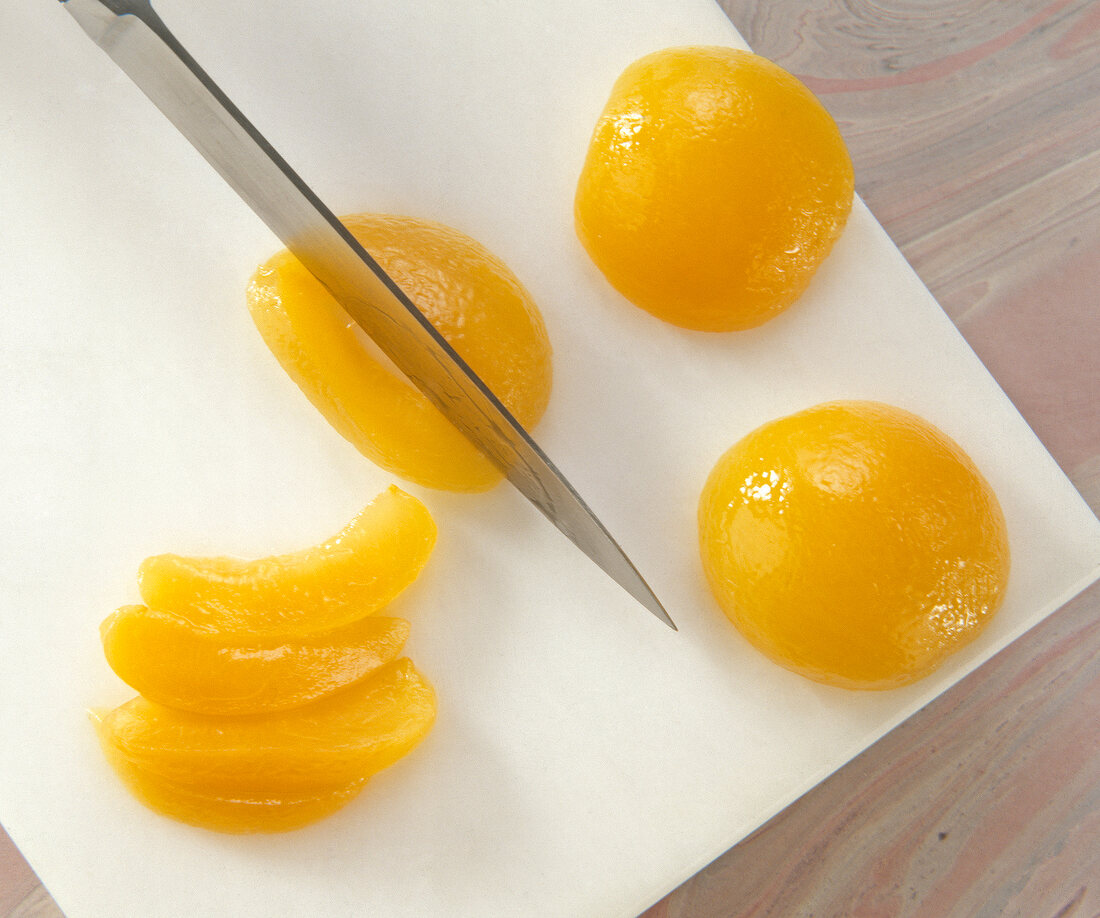 Apricot being cut into slices on chopping board