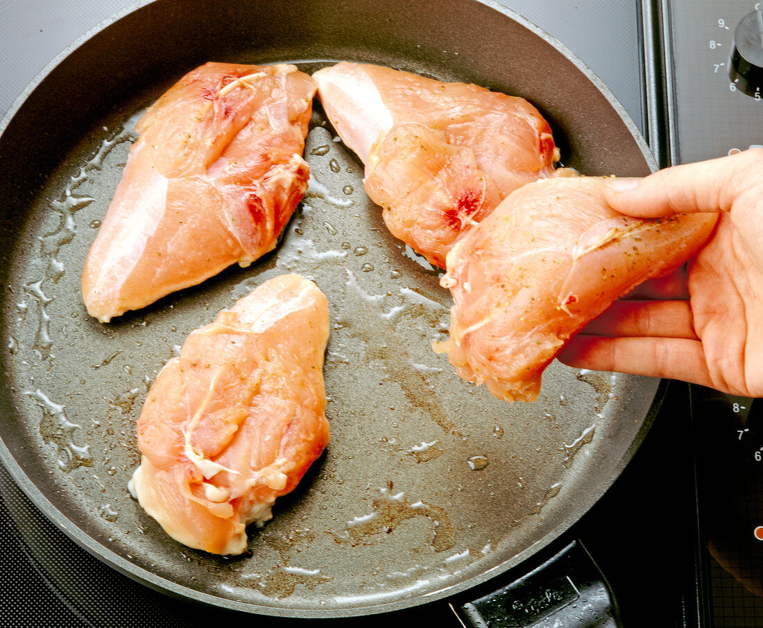 Close-up of frying chicken breast fillets in pan