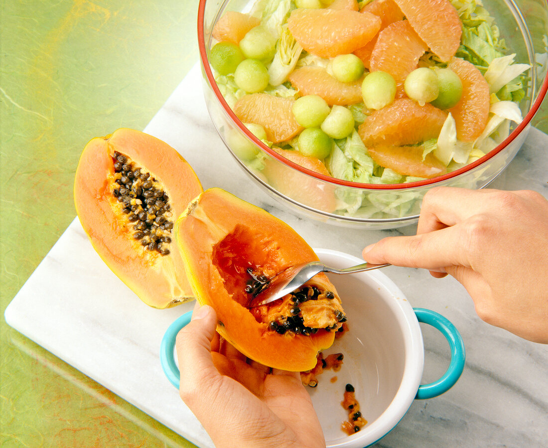 Removing papaya seeds with spoon