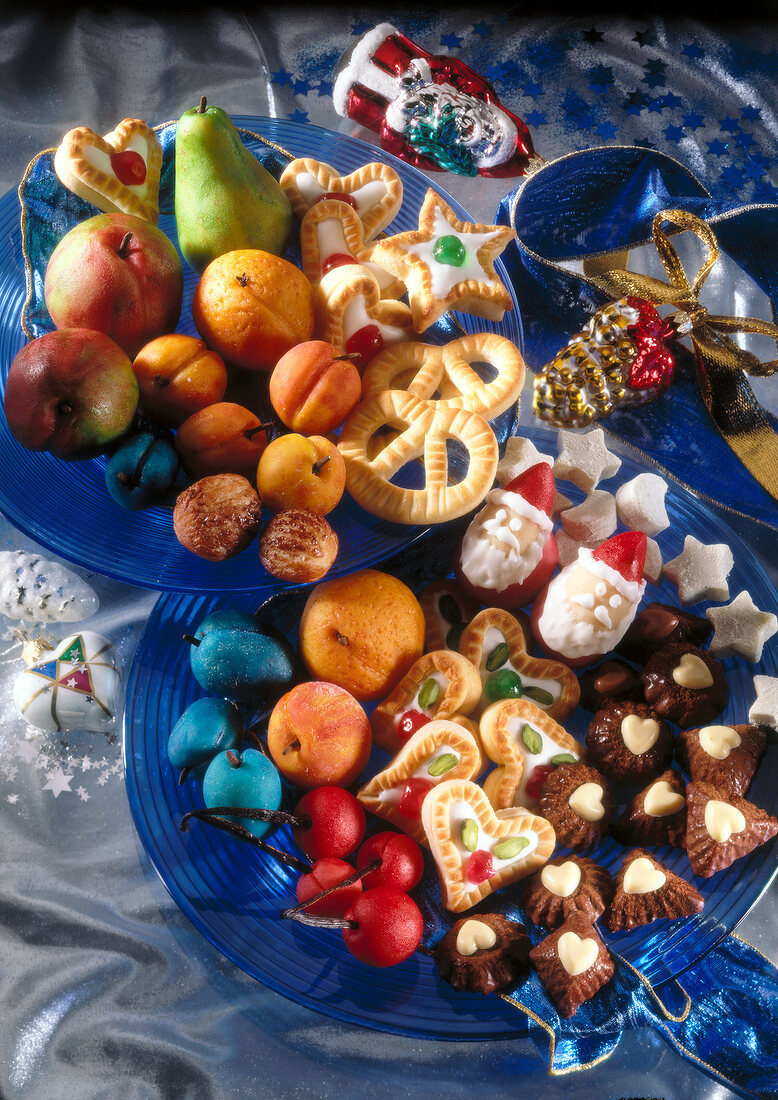 Different type of fruits and marzipan cookies on plates