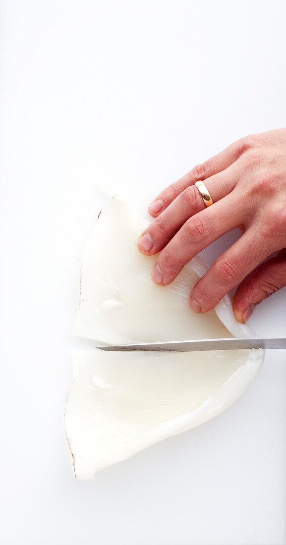 Squid's body bag being cut into pieces with knife, step 2