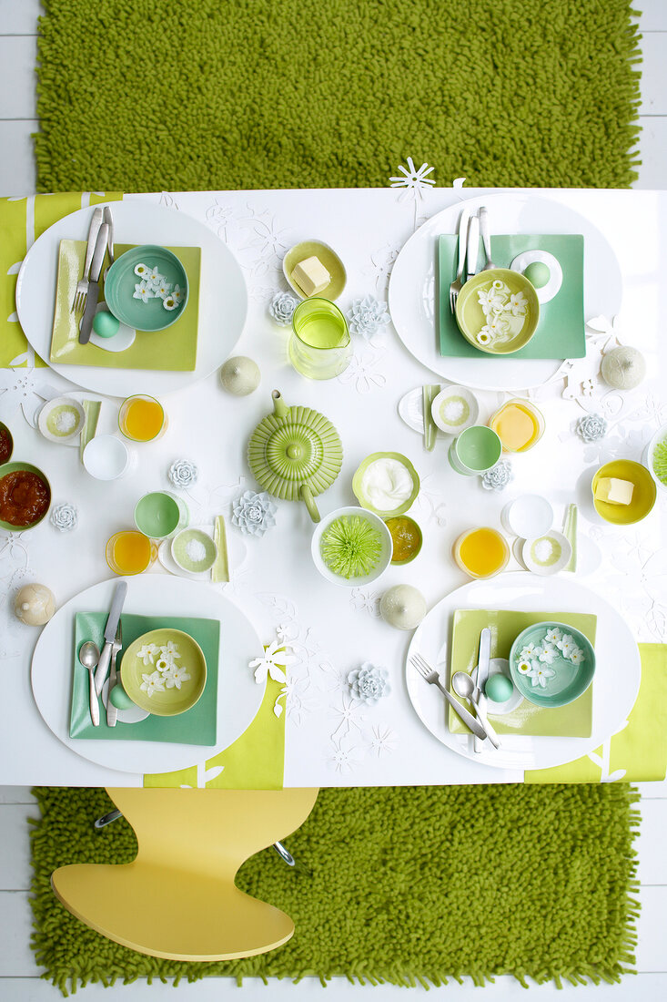Breakfast table setting in green and white for Easter, overhead view