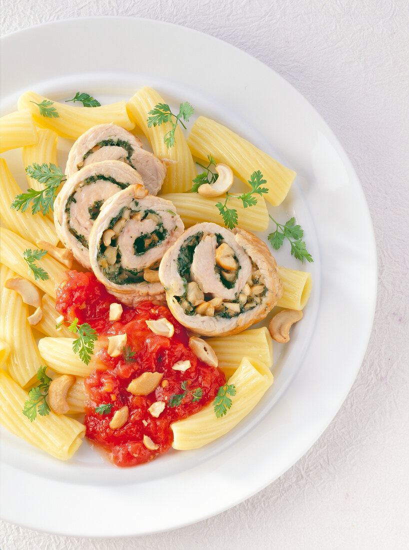 Turkey rolls with tomato sauce and pasta on plate