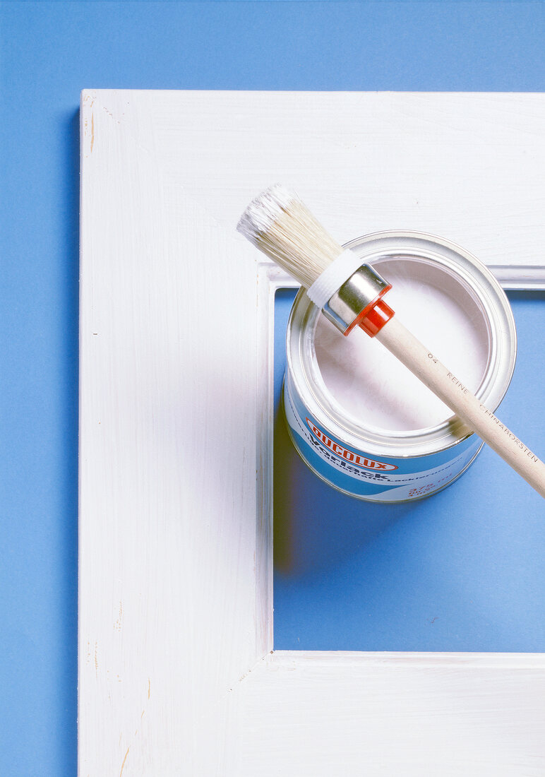 Close-up of half painted photo frame with paint brush and white paint tin on side