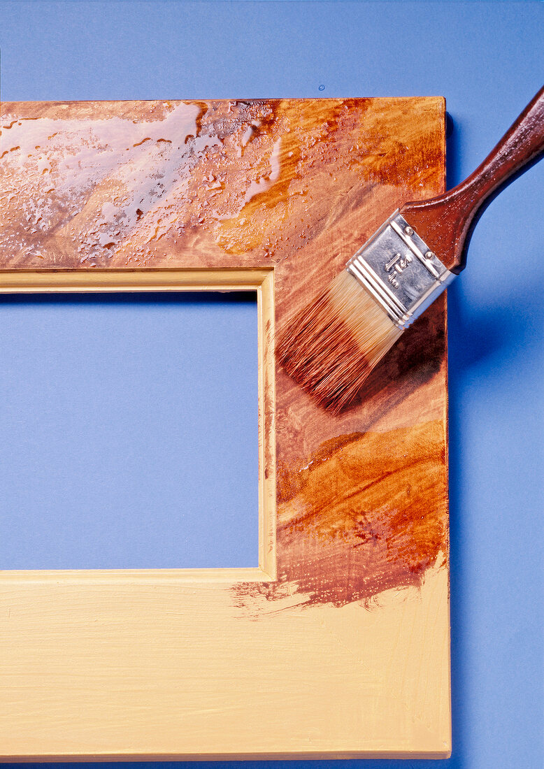 Close-up of half painted photo frame with paint brush