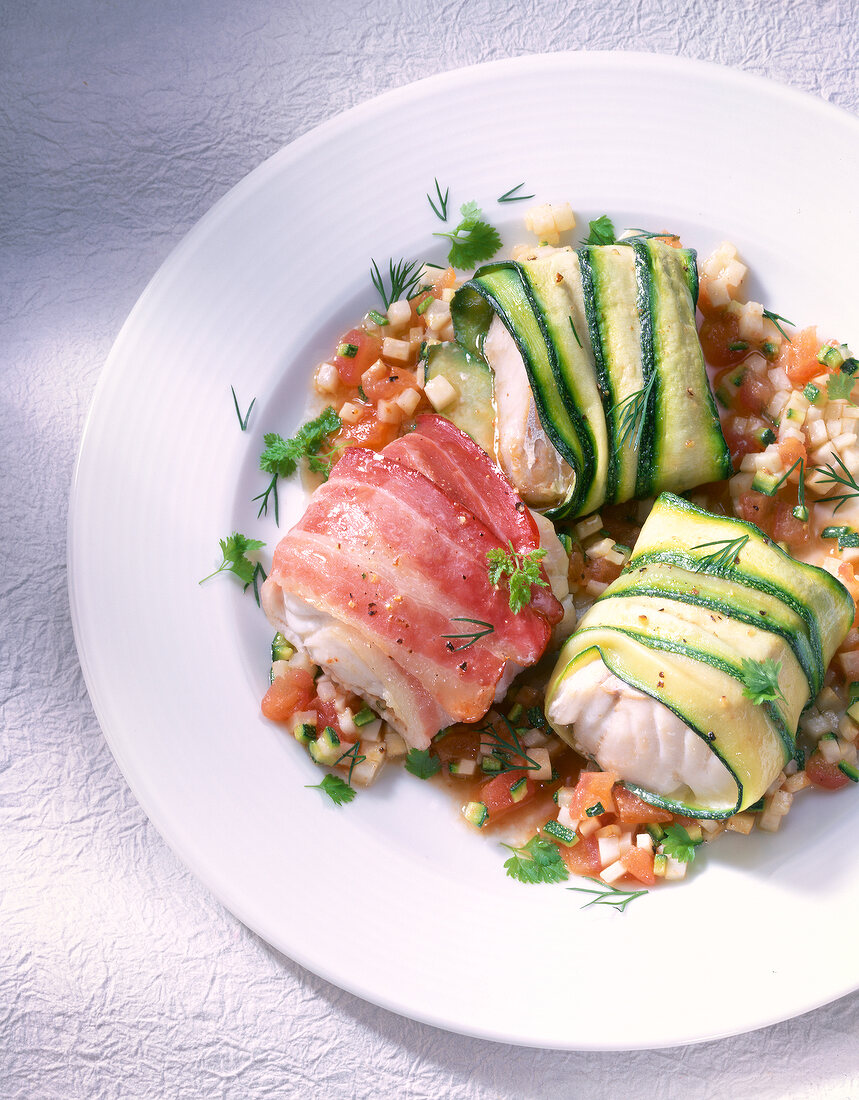 Fish parcels with saithe, zucchini and bacon on plate