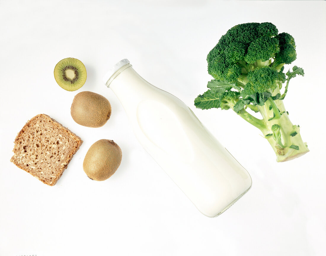 Milk bottle, broccoli, slice of bread and kiwi on white background
