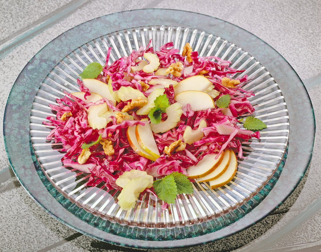 Red cabbage salad with pear and walnuts on glass plate