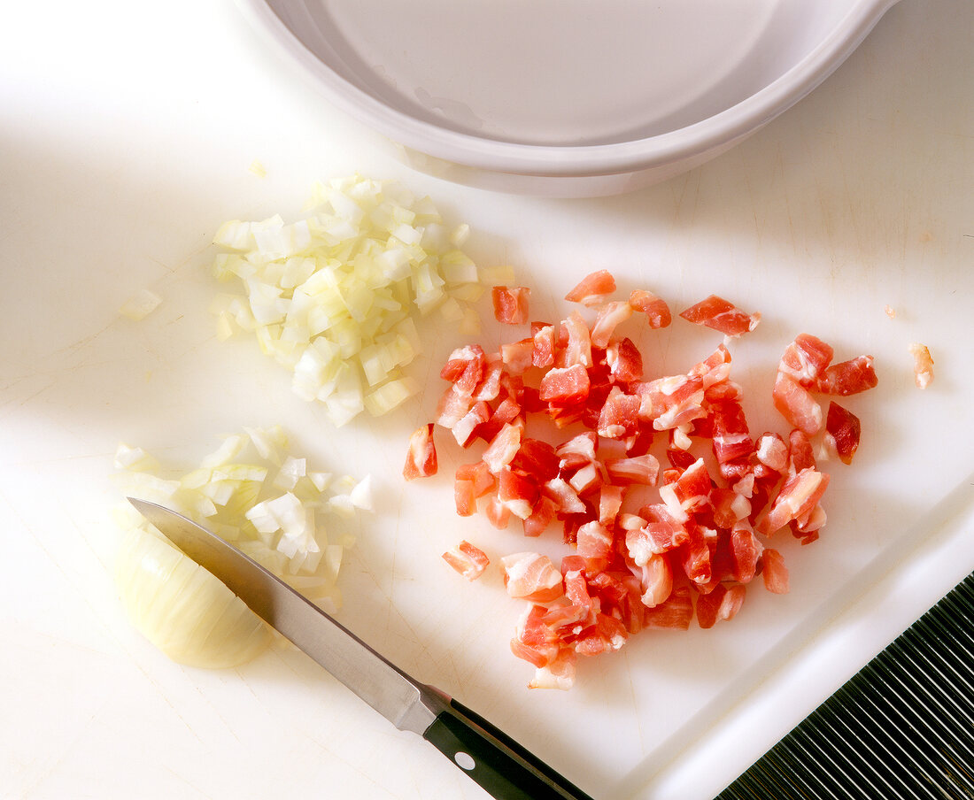 Chopped pieces of onions bacons and onions on cutting board