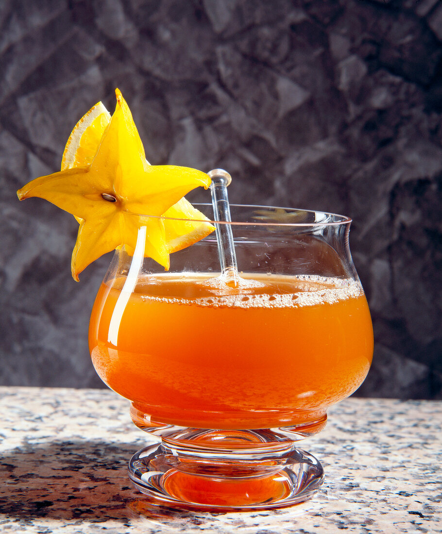 Orangentee-Punsch im Glas mit Karambolescheiben angerichtet