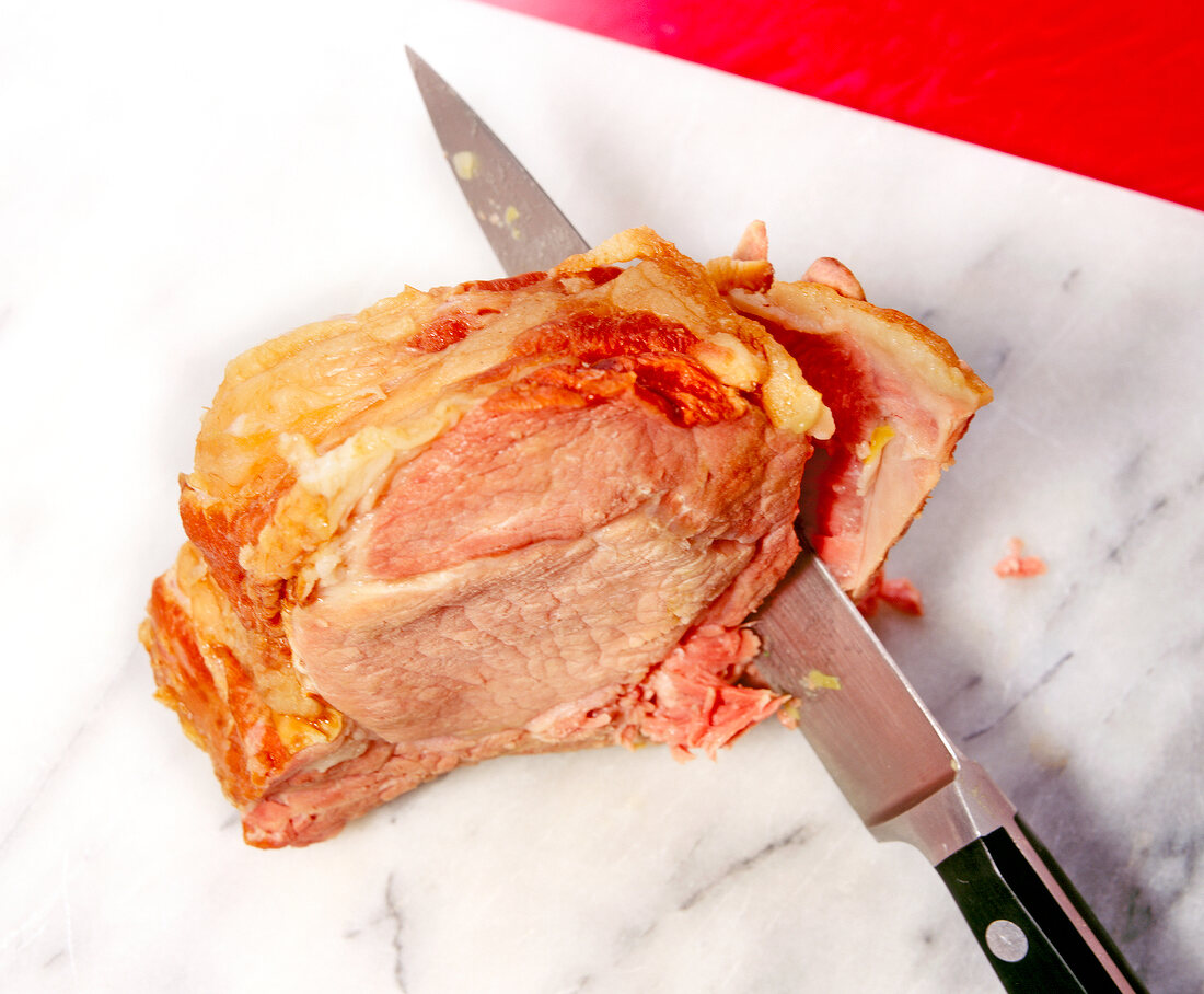 Separating the meat from the bone with knife for pea soup with smoked pork