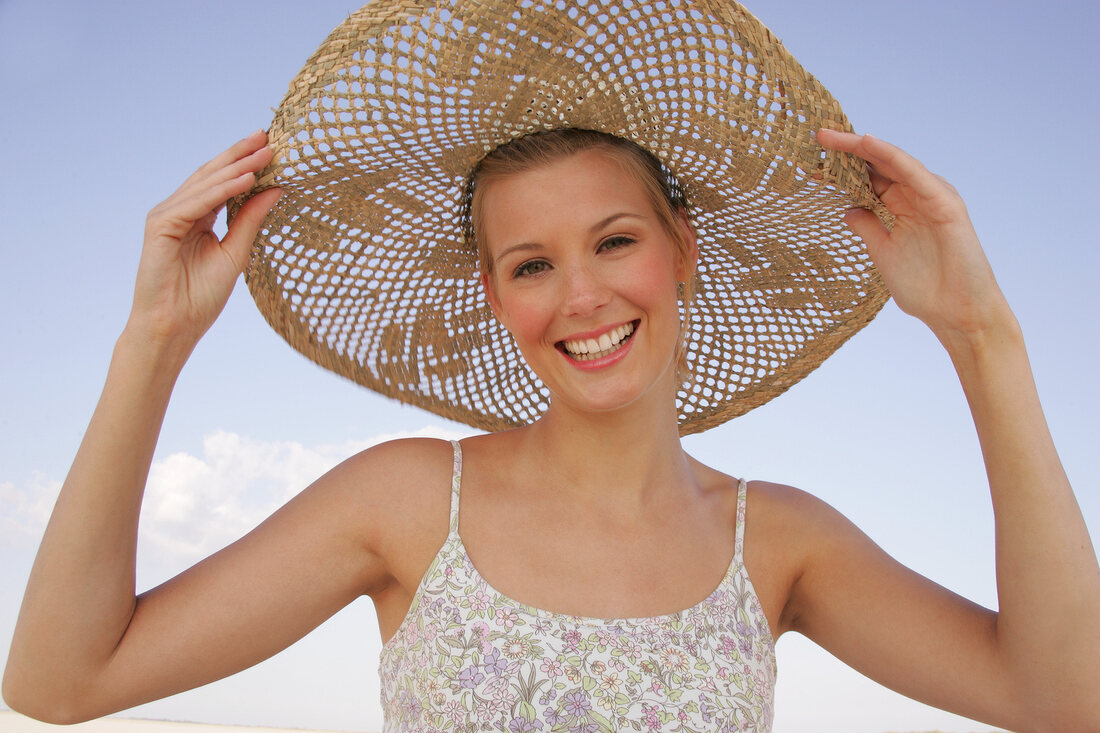 Jennifer Fröhliche junge Frau am Strand mit einem großen Strohhut