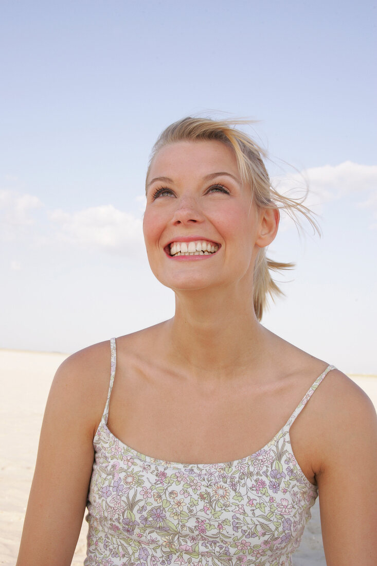 Happy woman wearing floral patterned top looking up and laughing