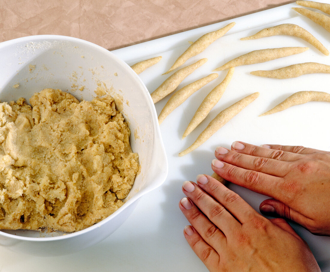 Potato dough being rolled in long rolls on board