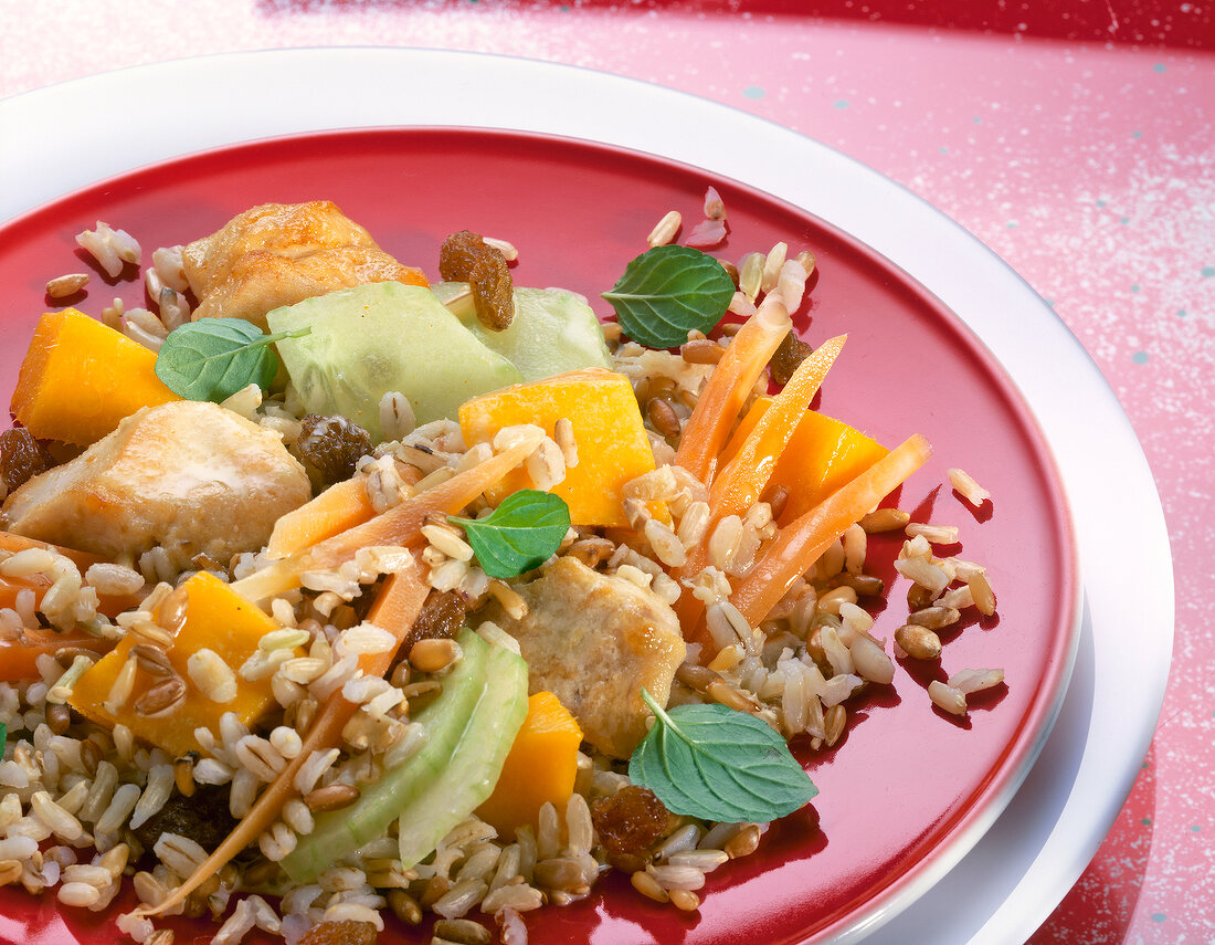 Rice salad with mango, cucumber, raisins and chicken breast fillet on plate