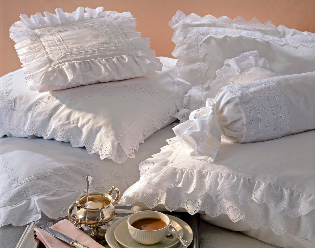 Pillows and neck roll of white cotton with lace ruffles