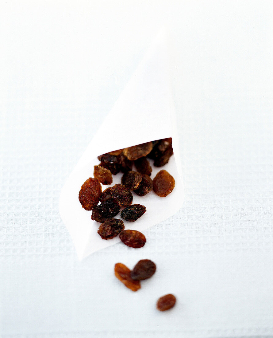Close-up of partly spilled raisins from paper bag on table