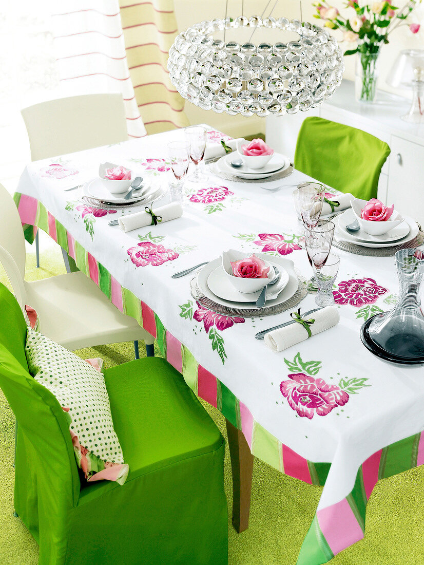Chairs, lamp and table laid with floral tablecloth and plates